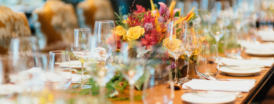 A table with plates, glasses, spoons, napkins, and flowers